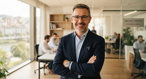 Professional portrait of a middle-aged Spanish business manager with glasses in a modern Pontevedra office, natural warm lighting, wearing a navy blazer, confident and approachable expression.